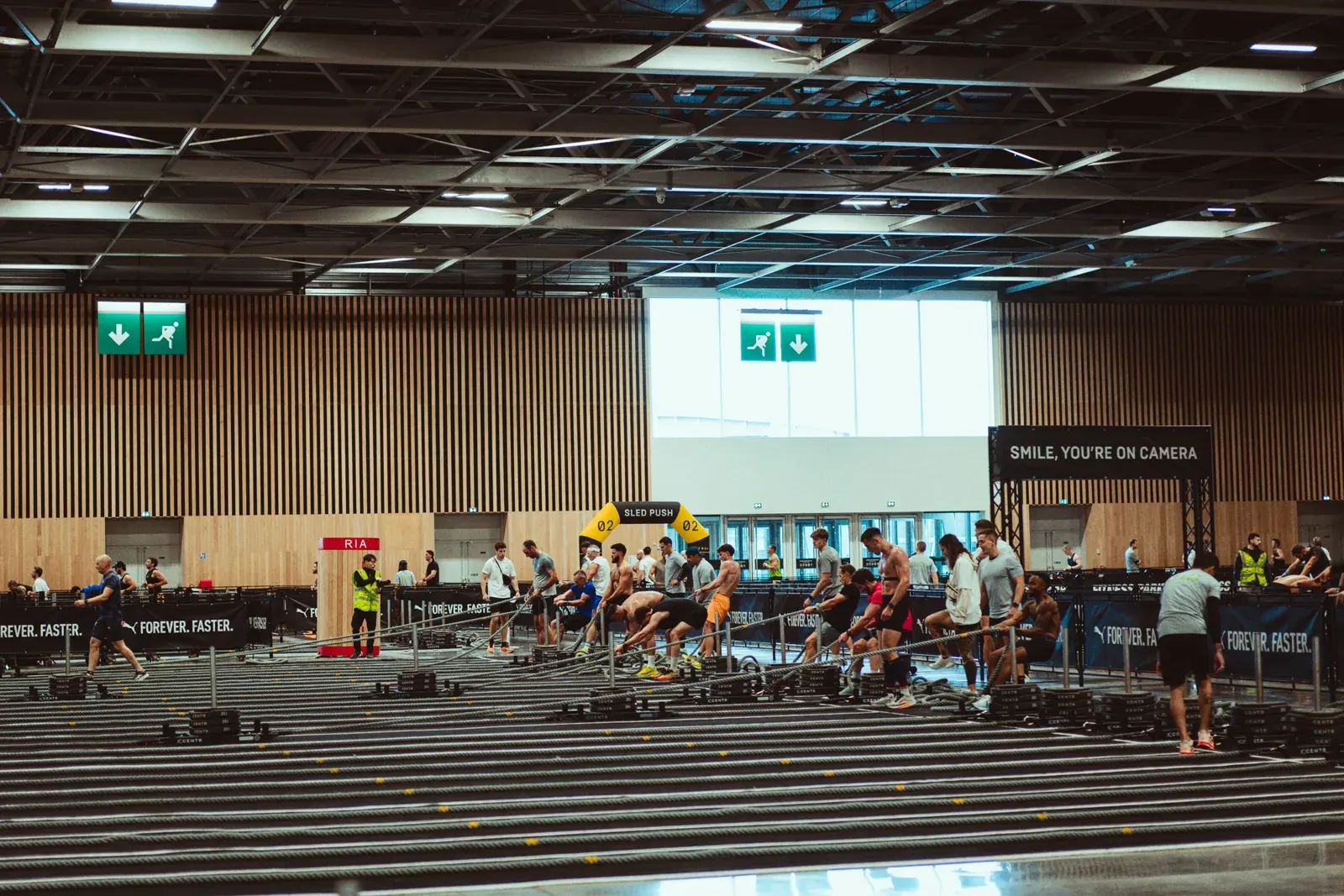 Hall d'une course Hyrox avec la piste de course et les stations, vu de loin